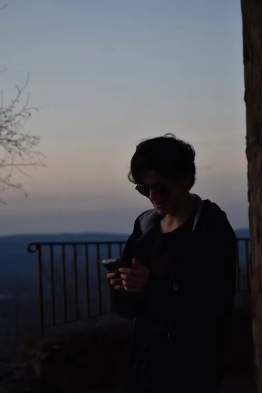 Someone checking their phone on a balcony at dusk
