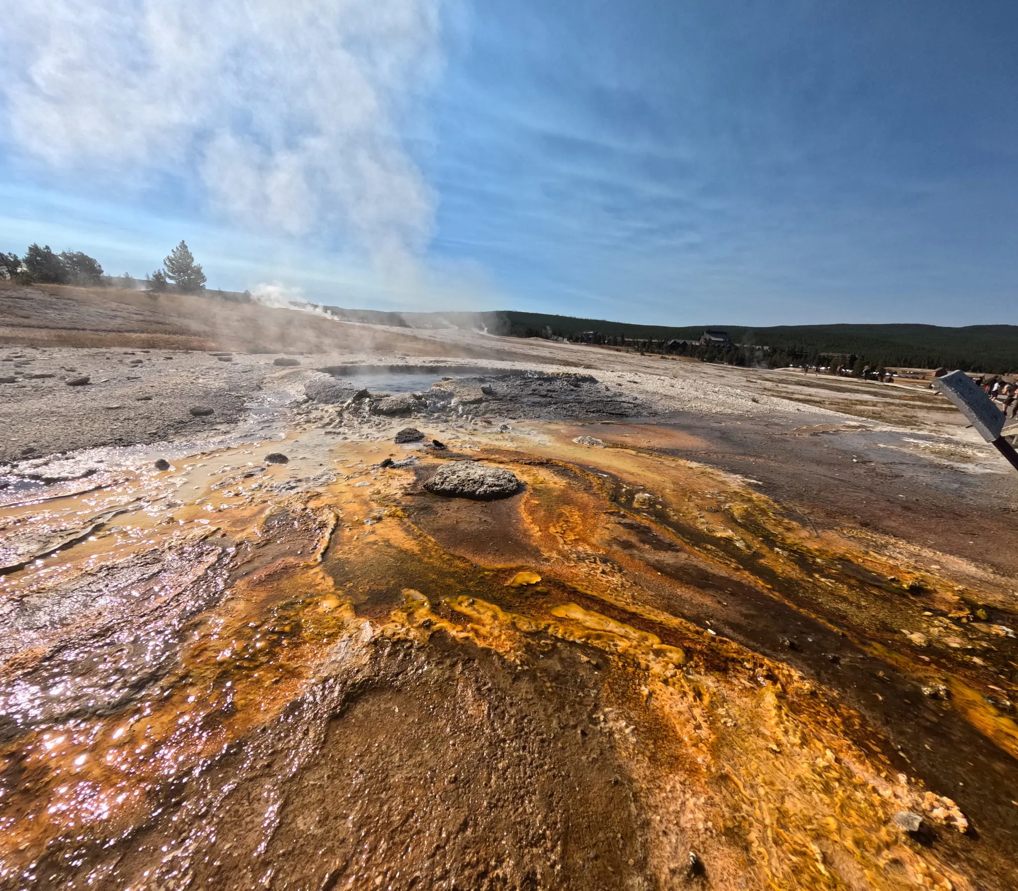 Steam rising from orange hot spring runoff in Yellowstone