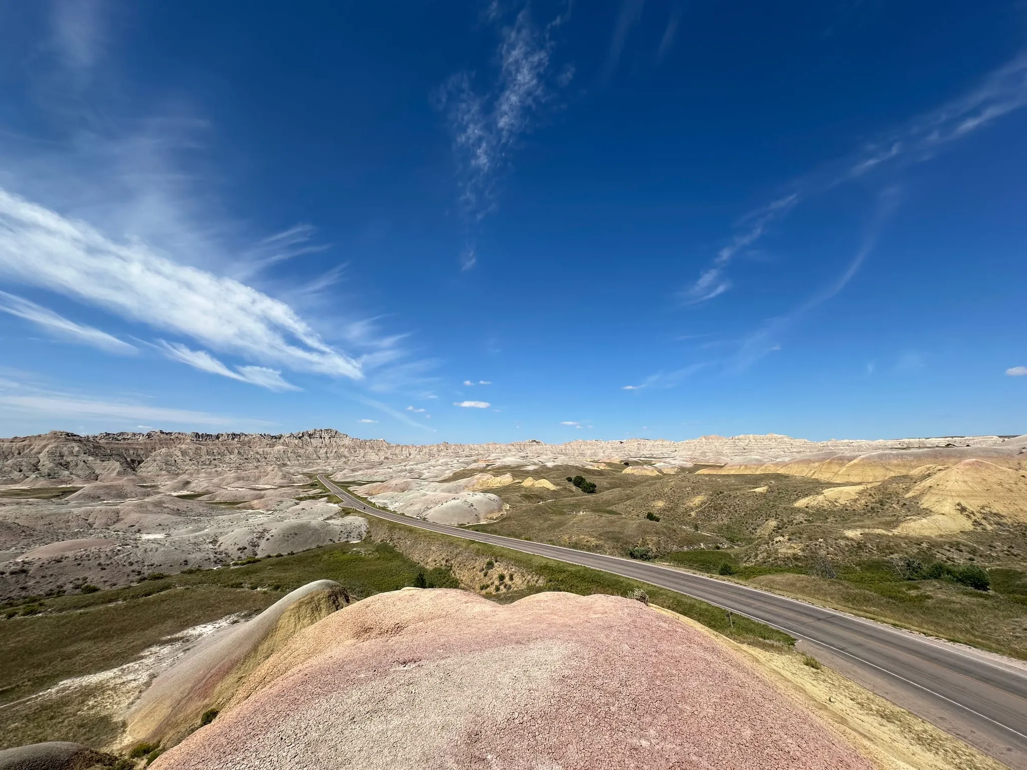 A road along a ridge in the Badlands under wispy clouds