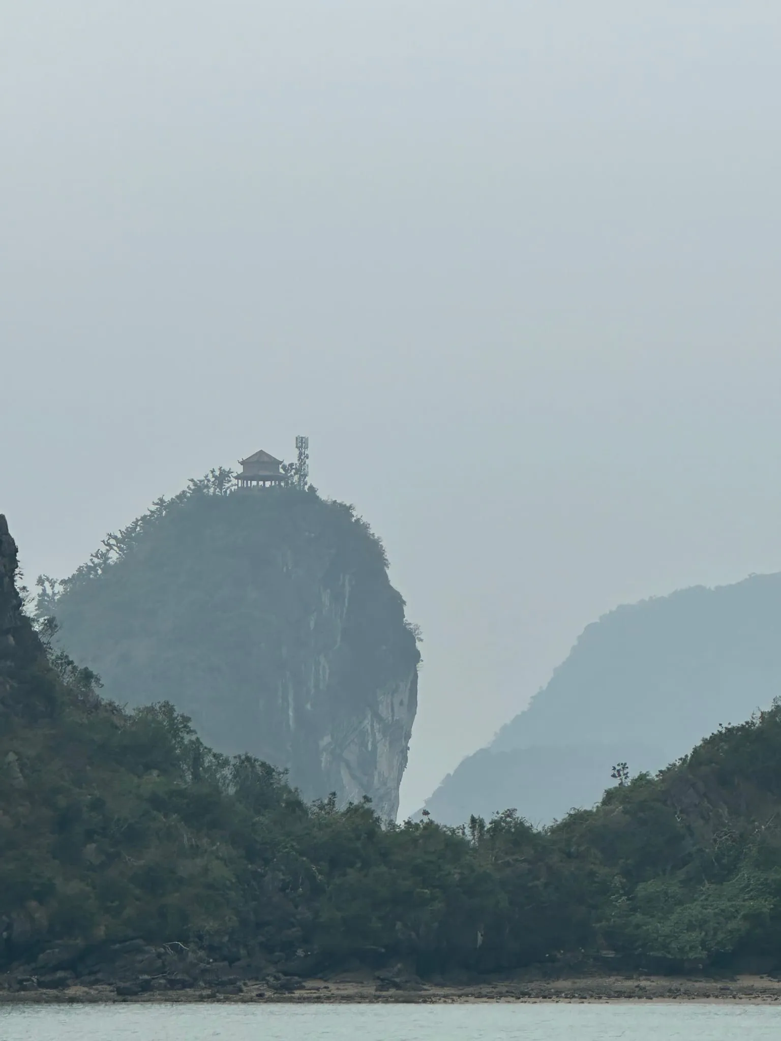 A limestone peak in haze in Ha Long Bay