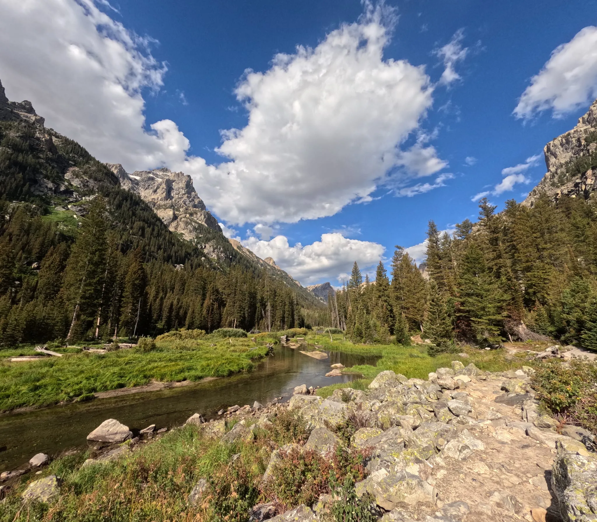 A creek winding through a valley below the Tetons